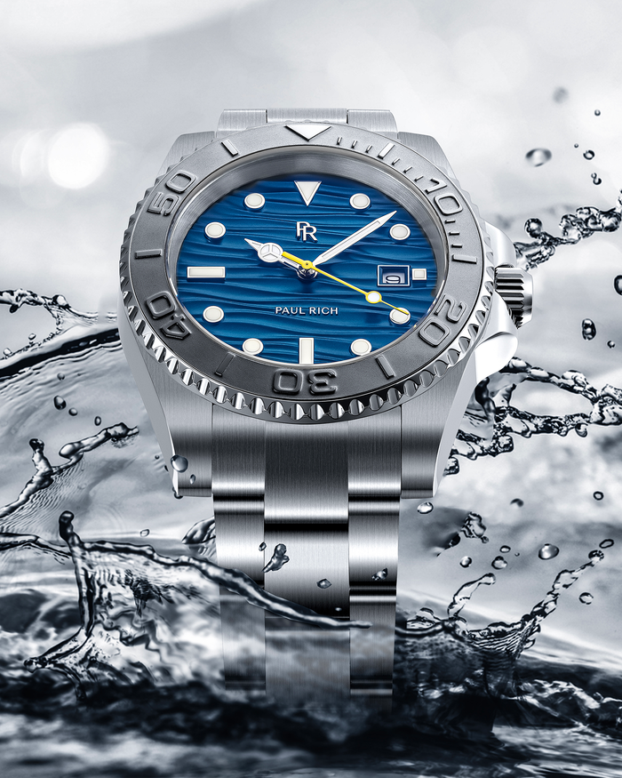 Stainless steel watch with a blue wave-textured dial shown against splashing water, highlighting the bezel, bracelet, and yellow seconds hand.
